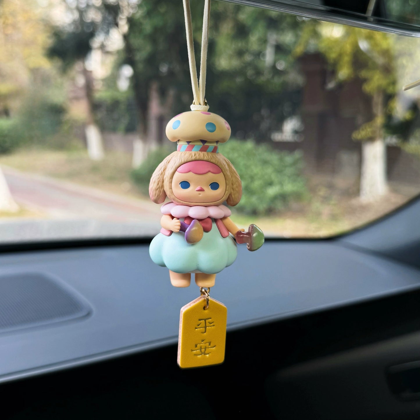 Luvbubu BubbleBear charm doll in pink outfit with bear hoodie and crystal ball, hanging on car dashboard with Lucky tag
