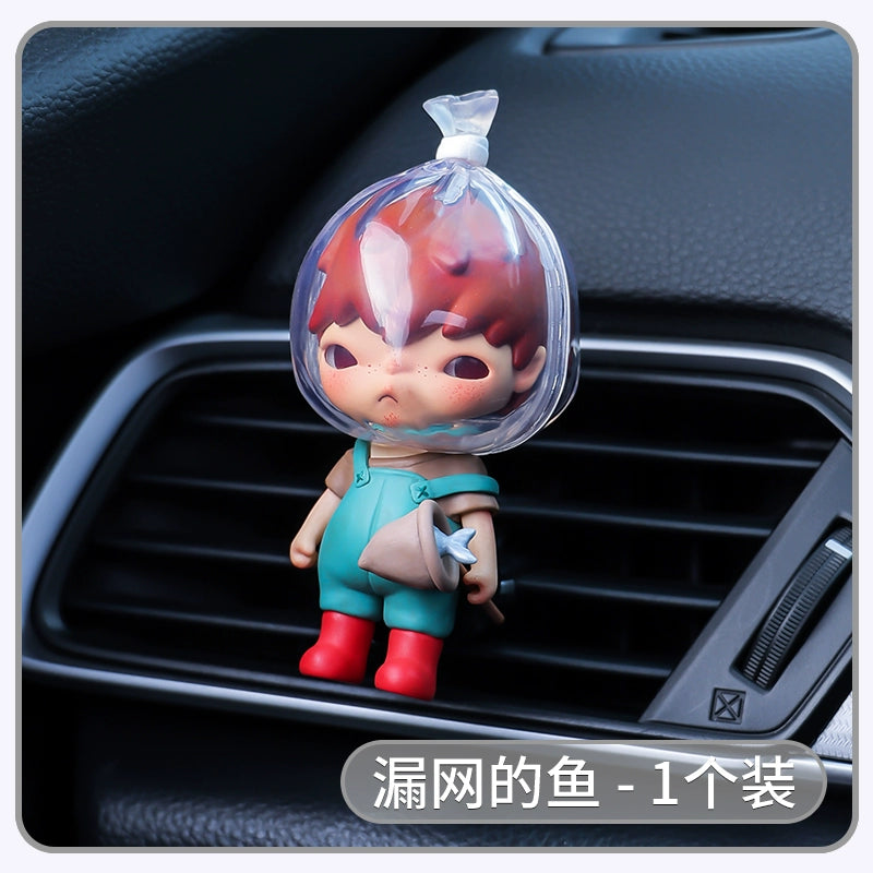 Car air freshener shaped like a cartoon character with red hair and blue overalls on a car vent.