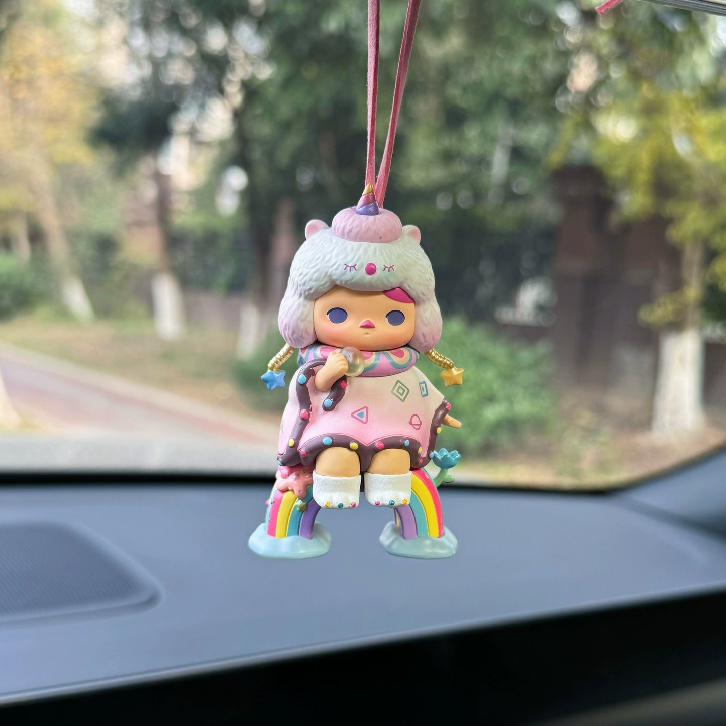 Luvbubu BubbleBear charm doll in pink outfit with bear hoodie and crystal ball, hanging on car dashboard with Lucky tag