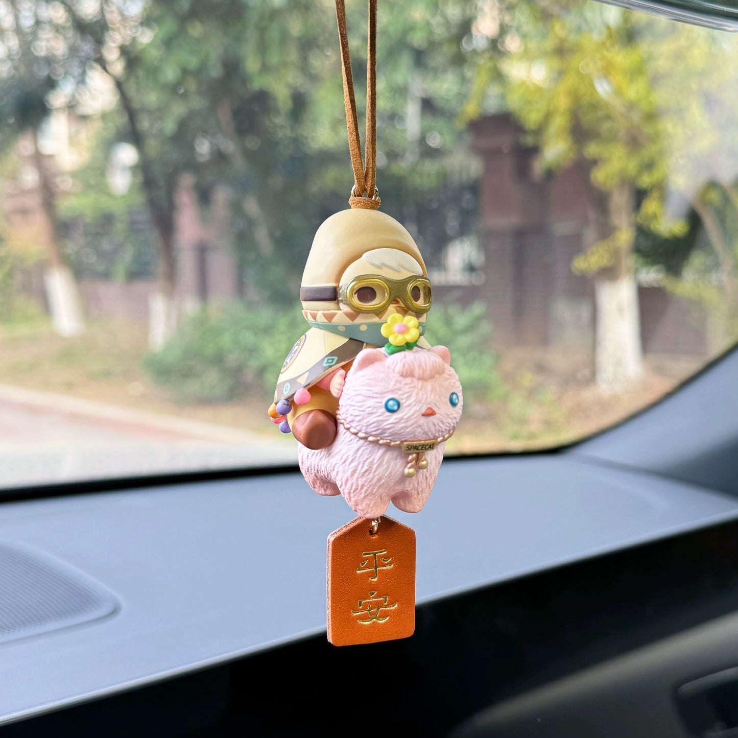 Luvbubu BubbleBear charm doll in pink outfit with bear hoodie and crystal ball, hanging on car dashboard with Lucky tag
