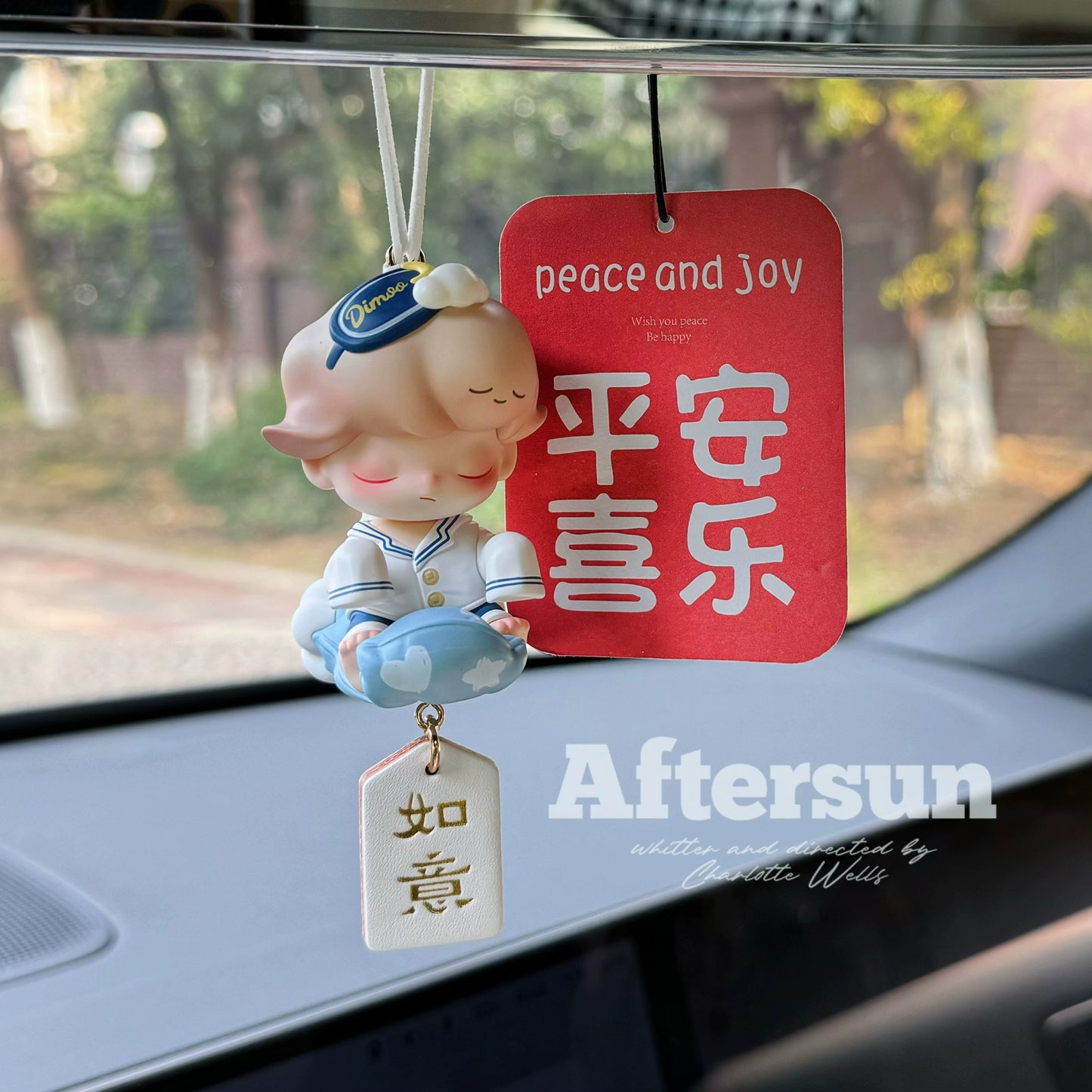 Dreamoo sailor figurine with blue orb and red Peace & Joy tag on car dashboard – soft aesthetic collectible charm