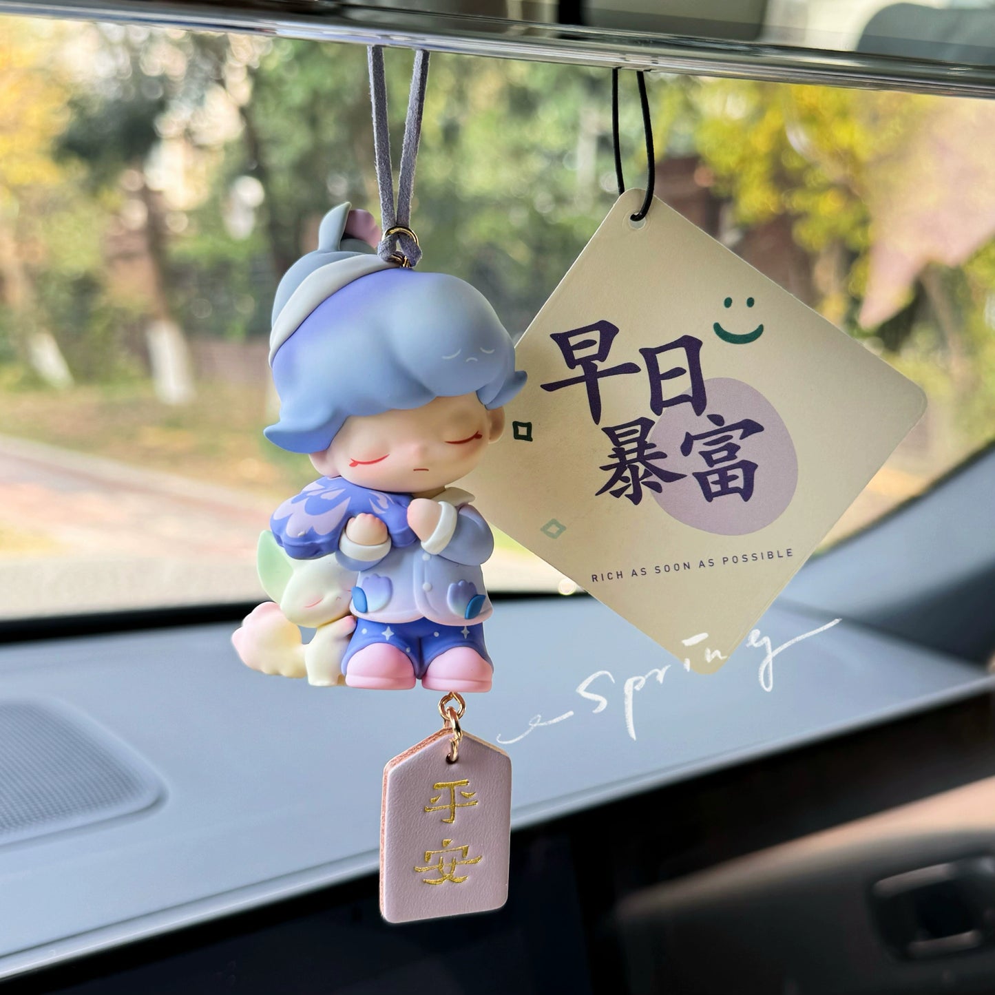 Dreamoo sailor figurine with blue orb and red Peace & Joy tag on car dashboard – soft aesthetic collectible charm